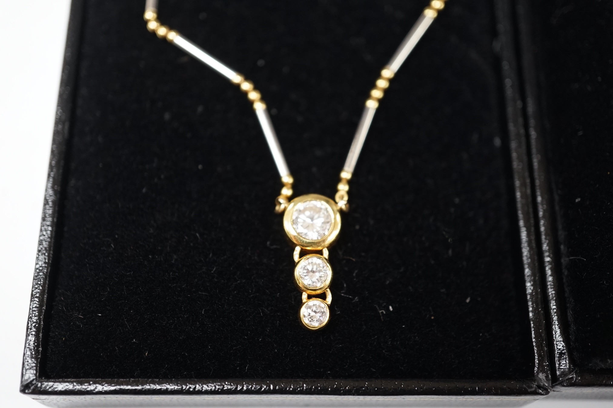 A modern yellow and white metal (stamped 18kt and Pt850), graduated three stone diamond set pendant necklace, 42cm, gross weight 7.1 grams and a an Italian Uno-A-Erre 18ct gold and solitaire diamond set necklace, 46cm, g
